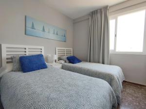 sypialnia z 2 łóżkami z niebieskimi poduszkami i oknem w obiekcie Apartamento Veracruz - Primera Linea de Playa w mieście Benidorm +25 zdjęć