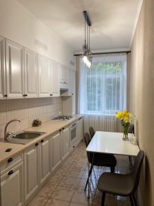 a kitchen with white cabinets and a table with chairs at 2-комнатная квартира на Соборной in Mykolaiv