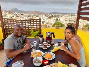a man and a woman sitting at a table with food at Casa Bom Dia in Mindelo