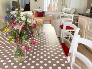 un jarrón lleno de flores sentado en una mesa en La Maison des Remparts - Gite 3 etoiles pour 8 pers a Loches, en Loches