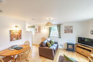 a living room with a couch and a table and a television at Bracken Lodge 6 with Hot Tub in Belladrum