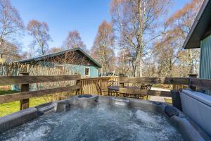 a hot tub in a yard next to a fence at Bracken Lodge 6 with Hot Tub in Belladrum