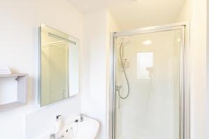 a white bathroom with a shower and a sink at Bracken Lodge 6 with Hot Tub in Belladrum +19 photos