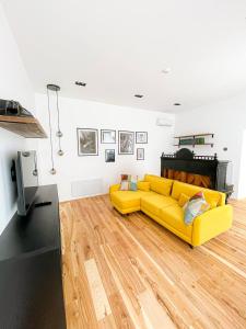 a living room with a yellow couch and a piano at Poetry Apartments in the city center in Kharkiv