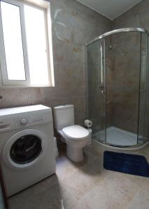 uma casa de banho com um WC, um chuveiro e uma máquina de lavar roupa em F7 Modern and Bright Apartment in Malta em Msida