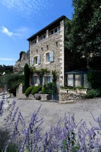 una casa de piedra con flores púrpuras delante de ella en Le Bonheur, en Gordes