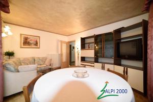 un soggiorno con tavolo e TV di Casa Dolomiti - BERTA a Campitello di Fassa