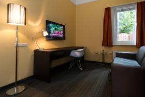 Habitación de hotel con escritorio y TV. en Golden Mansion Aparthotel en Ámsterdam