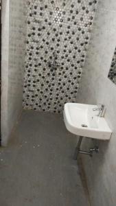 a white sink in a bathroom with a tile wall at S G INTERNATIONAL PATNA in Patna