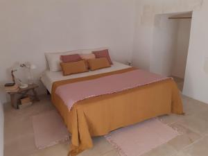 1 dormitorio con 1 cama con manta amarilla y almohadas en Casa Baronessa, en Ceglie Messapica