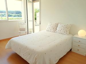 białe łóżko w białej sypialni z oknem w obiekcie Cerqueira's House w mieście Vila Nova de Cerveira