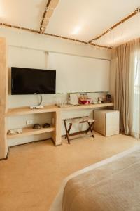 a living room with a desk with a television on a wall at Casa de Areia in Jericoacoara