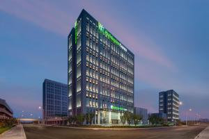 a tall building with a green sign on it at Holiday Inn Express Rongcheng Science and Technology Park in Rencheng