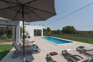 un patio con sedie, ombrellone e piscina di Villa Luna a Brtonigla (Verteneglio)