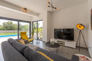 un soggiorno con divano grigio e TV di Villa Luna a Brtonigla (Verteneglio)