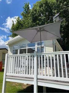 a white porch with an umbrella in front of a house at Kellys Holiday Homes 24 Willerby 2 bedrooms caravan in Weeley