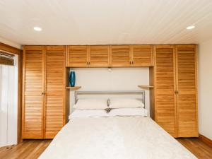 a bedroom with wooden cabinets and a bed at 2 Burnside Place in Kirkcudbright