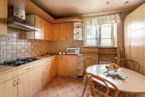 kuchnia z drewnianymi szafkami, stołem i kuchenką mikrofalową w obiekcie Apartament przy Parku w Kudowie Zdroju