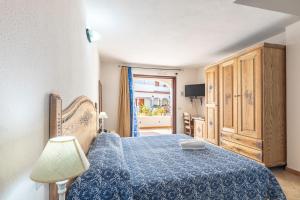 a bedroom with a bed with a blue bedspread at Hotel Bonsai in San Teodoro