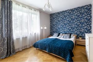 a bedroom with a bed and a blue and white wall at Apartament przy Parku in Kudowa-Zdrój