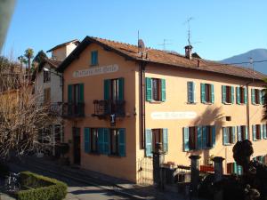 a yellow building with green shuttered windows on a street at Il Grifo in Lenno