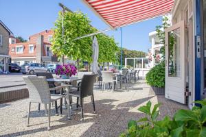 a patio with tables and chairs and an umbrella at Hotel de Branding in De Koog