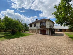 una casa antigua con balcón en una entrada de grava en Maison chaleureuse avec un grand jardin, en La Bonneville