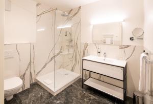 ein Bad mit einer Dusche, einem WC und einem Waschbecken in der Unterkunft Boutique Hotel Dom - Rooms & Suites in Graz