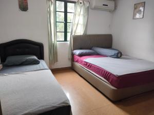 two beds sitting in a room with a window at ASH HOTEL in Seremban