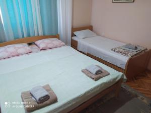 two beds in a small room with towels on them at Apartment & Rooms Aleksandar in Golubac