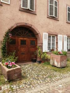 ein Gebäude mit einer Holztür und ein paar Blumen in der Unterkunft Gîte Le Patio in Kaysersberg