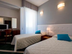 a hotel room with two beds and a television at Hotel Metropol in Senigallia