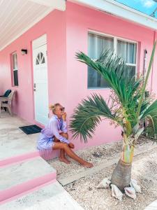 a woman sitting outside of a pink house at Tropical View Villas in Hartswell