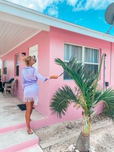Kobieta stoi przed różowym domem. w obiekcie Tropical View Villas w mieście Hartswell