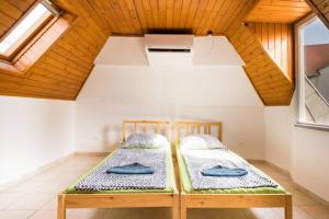 two beds in a room with a wooden ceiling at AZURE house in Keszthely