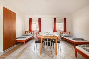 - une salle à manger avec des lits, une table et des chaises dans l'établissement AZURE house, à Keszthely