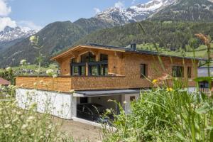 a house on a hill with mountains in the background at Chalet Vega - Arlberg Holiday Home in Pettneu am Arlberg