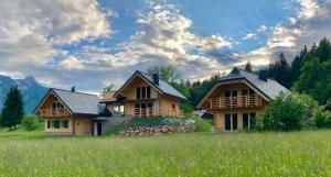 2 grandes maisons en bois dans un champ arboré dans l'établissement Chalet Camporosso Rosenstein, à Camporosso in Valcanale