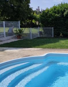 a blue swimming pool in a yard with a white fence at Villa SAINT-PRIVAT in Pouzilhac