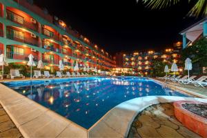 a swimming pool in front of a hotel at night at Hotel Kokiche in Sunny Beach