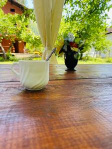 kubek kawy na drewnianym stole z wazonem kwiatów w obiekcie Къща за гости Станеви w mieście Ribarica