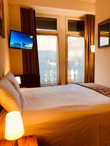 a bedroom with a bed with a tv and windows at Hotel Harder Minerva in Interlaken