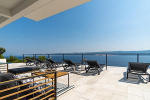 een balkon met stoelen en tafels en uitzicht op het water bij Seaview Villa Marila with a private pool with hydromassage, 3 en suite bedrooms, 1km from beach in Lokva Rogoznica