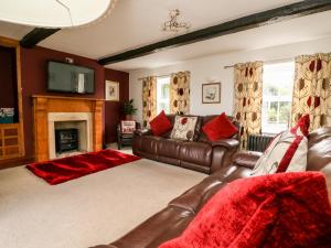 een woonkamer met een leren bank en een open haard bij The Cottage at Nidderdale in Harrogate