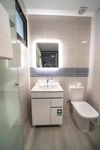 een badkamer met een wastafel, een toilet en een spiegel bij Coração da Madeira in Curral das Freiras