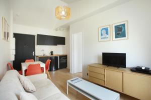 a living room with a couch and a tv at Residence Boulogne Centre le passage by Studio prestige in Boulogne-Billancourt