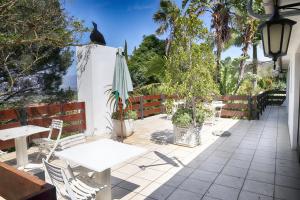 a patio with tables and a umbrella and trees at Auberge de Courtrai in Paarl