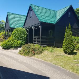 a black house with a green roof next to a road at Owk Korona in Mikoszewo