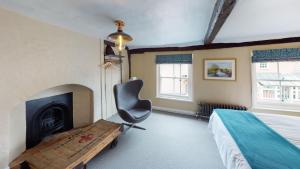 戴德姆的住宿－The Marlborough Dedham，一间卧室配有一张床、一把椅子和一个壁炉