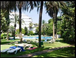 una piscina con sillas, una mesa y palmeras en Jardines del Mar ,Casa Apolonia, en Marbella